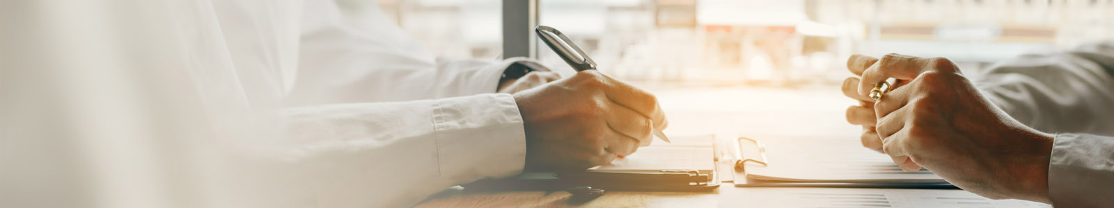 two peopel sit at opposite sides, one is doing notes on a notebook