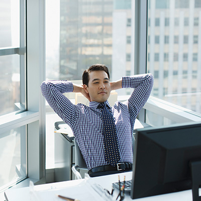 a gentleman sitting in his office reading documents with his laptop.