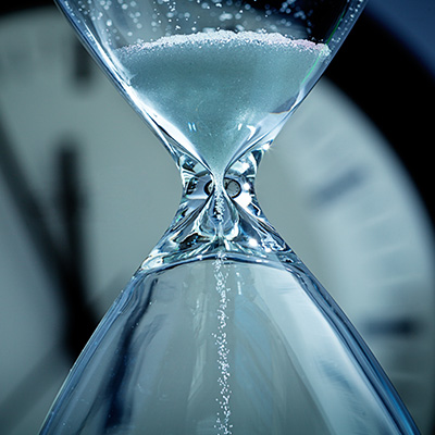 an hourglass with a clock background