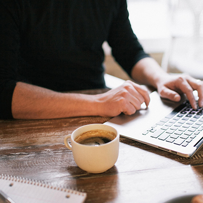 a man using laptop with a black coffee on the table