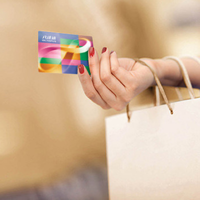 a lady's hand holding an octopus card and paper shopping bag