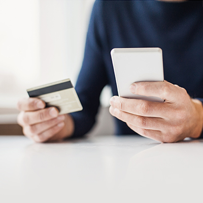 man holding mobile and a credit card