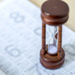 an wooden hourglass on a paper annual calendar