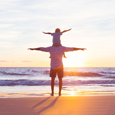 a kid on an adult's shoulder, spreading hands on facing to the sea