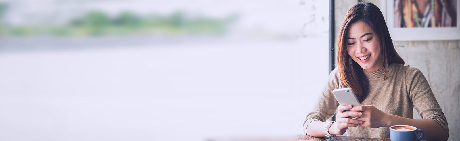 一位女士在咖啡店內看著她的手機