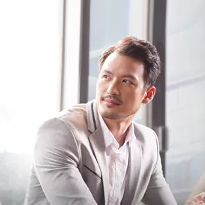 身著灰色西裝的成功商人坐在窗邊，微笑著回首