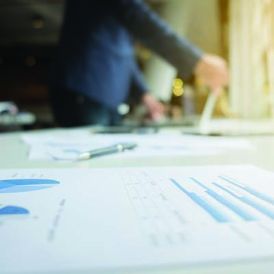 一個男人在用平板，桌上有一張報告書