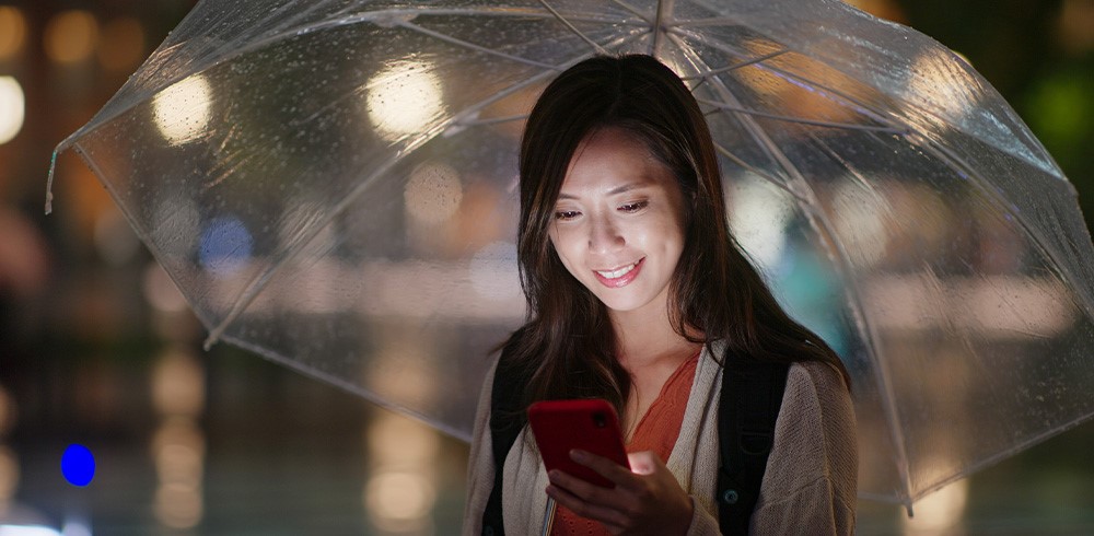 女士在下雨天打開手傘及使用手機